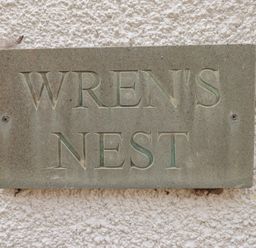 A sign displaying the name WREN'S NEST at Wrens Nest in Slapton
