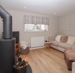 A snug with a wood stove and sofa at Wrens Nest in Slapton