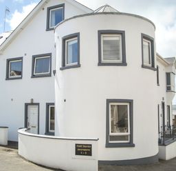 The exterior of a white building with gray window frames and a curved wall at Apartment One in Duncannon County Wexford