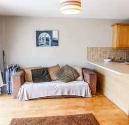 A sofa with cushions beside a kitchen counter in a living area at Apartment One in Duncannon County Wexford