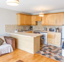 A kitchen with wooden cabinets appliances and a sofa with cushions at Apartment One in Duncannon County Wexford
