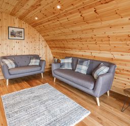 A wooden paneled living room with two gray sofas and a rug at Bluebell in St Harmon near Rhayader