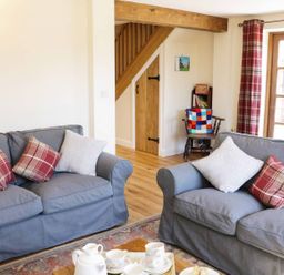 A living room with two gray sofas with cushions and a wooden coffee table with tea set at The Cider House in Leominster
