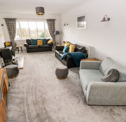 A living room with three sofas two side tables a floor lamp and a wood stove at The Dingle in Wisemans Bridge near Stepaside