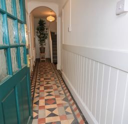 A hallway with an indoor plant and staircase at Still Waters in Swanage