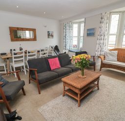 A living room with a coffee table and dining area at Still Waters in Swanage
