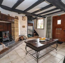 A living room with a fireplace wooden beams and a wooden door at Runnymede in Tewkesbury