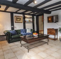 A living room with a green sofa a wooden coffee table and a wall-mounted TV at Runnymede in Tewkesbury