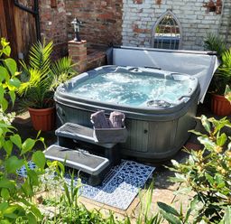 A hot tub with towels and plant pots in the garden at Runnymede in Tewkesbury