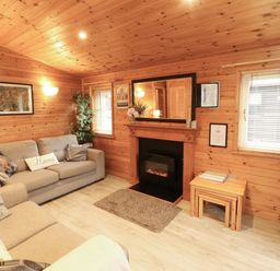 A living room with a sofa and a fireplace at The Fold, Number 28, Burnside Park near Keswick