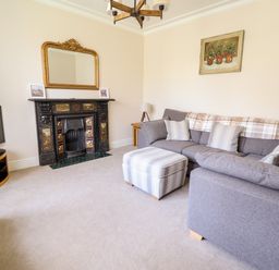 A living room with a gray sofa ottoman fireplace television and mirror at Craigside in Betws-Y-Coed