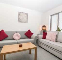 A living room with two grey sofas red and pink cushions wooden coffee table and window blinds at 16 Mythern Meadow in Bradford-On-Avon