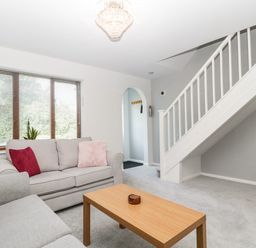 A living room with two sofas a wooden coffee table a TV stand under stairs and window blinds at 16 Mythern Meadow in Bradford-On-Avon
