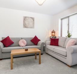 A living room with two grey sofas red and pink cushions wooden coffee table and window blinds at 16 Mythern Meadow in Bradford-On-Avon