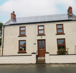 A two-story house with solar panels on the roof and a front gate at Brynawel in Llangynin near Llanboidy