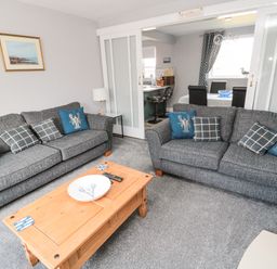 A living room with two grey sofas and a wooden coffee table at Fisherman's Row in Amble