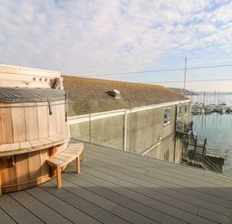 An outdoor deck with a wooden hot tub bench and a view of a waterfront with boats at 16 Arwenack Street in Falmouth