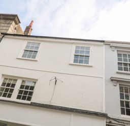 A row of white buildings with windows and a chimney at 16 Arwenack Street in Falmouth