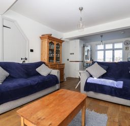 A living room with two sofas covered in blue throws and a wooden cabinet in the corner at Ferriwais in Appledore