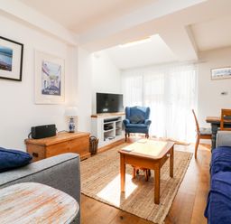 A living room with sofas a wooden coffee table a blue armchair a television and framed pictures on the wall at Ferriwais in Appledore