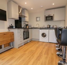 A kitchen with appliances washing machine oven and bar stools at The Granary in Helland near Bodmin