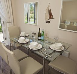 A dining area with a glass table set for four with beige chairs and a wall decoration of a sailboat at Crowthers in Dartmouth