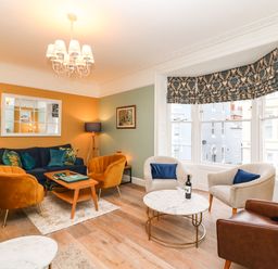 A living room with various armchairs a sofa a coffee table and a large window at Seaside House in Weymouth