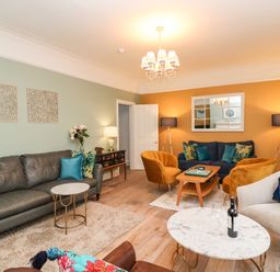 A living room with multiple sofas armchairs coffee tables lamps and wall art at Seaside House in Weymouth