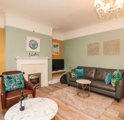 A living room with a brown leather armchair and a gray sofa with cushions by a fireplace at Seaside House in Weymouth