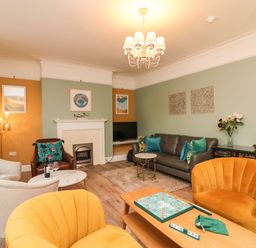 A living room with yellow armchairs a gray sofa a fireplace and a chessboard on a wooden table at Seaside House in Weymouth