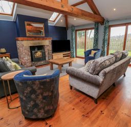 A living room with sofas a fireplace a television and large windows at Ridley Lodge West Thirston felton