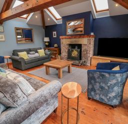 A living room with sofas chairs a wooden coffee table a fireplace and a television at Ridley Lodge West Thirston felton