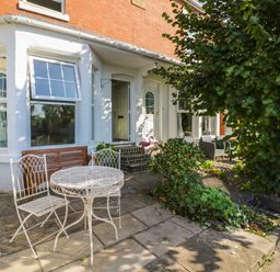 A patio area with white metal table and chairs a wooden bench and greenery at Florence Villas in Worcester