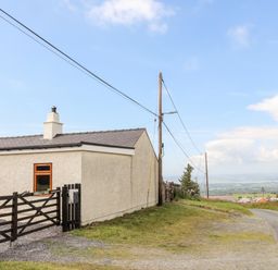 A country house near a road with power lines and a gate at Penrallt Fawr in Rhosgadfan near Waunfawr