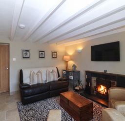 A living room with a sofa, fireplace, and television at 4 Bryn Llan, Aberdaron