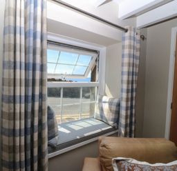 A living room with a window and cushions at 4 Bryn Llan in Aberdaron
