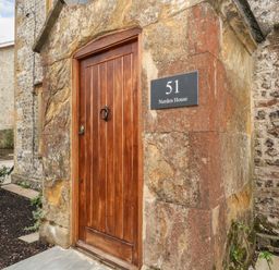 A wooden door set in a stone wall with a plaque reading 51 Norden House