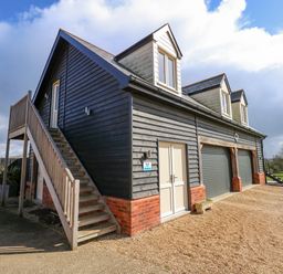 A two storey building with external wooden stairs and three dormer windows at The Attic in Blackborough End near Kings Lynn