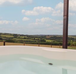 A hot tub overlooking a rural landscape at The Cadeleigh near Tiverton