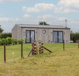 A house with a wooden exterior and a fence at The Pennymoor in Cadeleigh near Tiverton