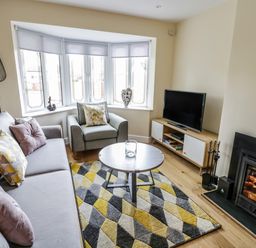 A living room with a sofa armchair round coffee table television and fireplace at Globe Cottage in Stratford-Upon-Avon