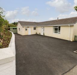 A single-story house with a paved driveway and small plants near the doors at Trem Y Morfa in Newport Pembrokeshire