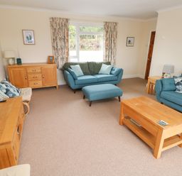 A living room with two blue sofas a wooden coffee table and sideboards at Trem Y Morfa in Newport Pembrokeshire