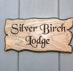 A wooden sign with the words Silver Birch Lodge on a gray wall at Silver Birch Lodge in Misterton