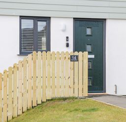 A black front door and window behind a wooden fence with a house number 14 Parc Delfryn Brynteg near Benllech