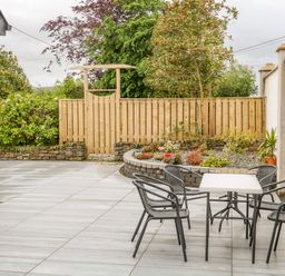 An outdoor patio with a table and four chairs near a garden bed and wooden fence at Wee Andy's Slavary near Buncrana County Donegal
