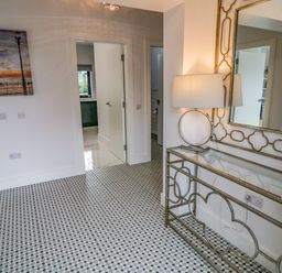 A hallway with patterned tile floor a table with round lamp and large decorative mirror at Wee Andy's Slavary near Buncrana County Donegal
