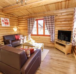 A living room with leather sofas a glass coffee table a television on a wooden stand and plaid curtains at Elm Lodge in Greetham Rutland