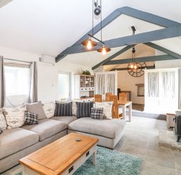 A living room with a sectional sofa and coffee table next to a wood stove at Polgear View Polgear Nr Redruth