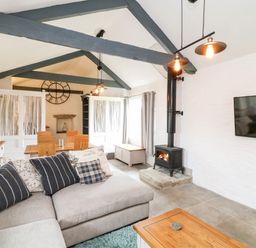 A living area with a sectional sofa dining table wood burning stove and mounted television at Polgear View Polgear Nr Redruth